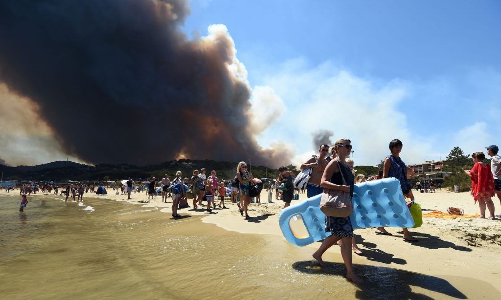 Incendios queman siete mil hectáreas de bosques y montes en Francia - People-walk-along-a-beach-near-Bormes-les-Mimosas-Photograph-Anne-Christine-Getty-Images-1024x614