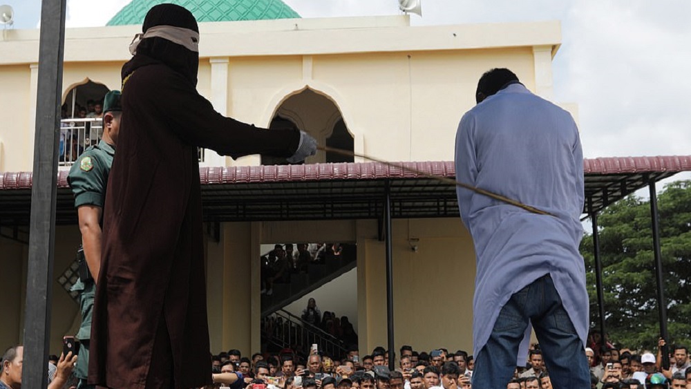 Azotan con vara a pareja por besarse en público en Indonesia - hombre-siendo-azotado