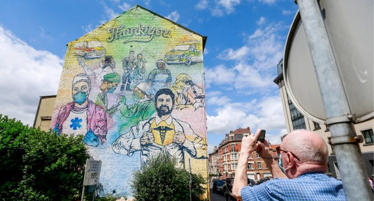 Artistas callejeros pintan mural en Bruselas para honrar a quienes luchan contra el COVID-19