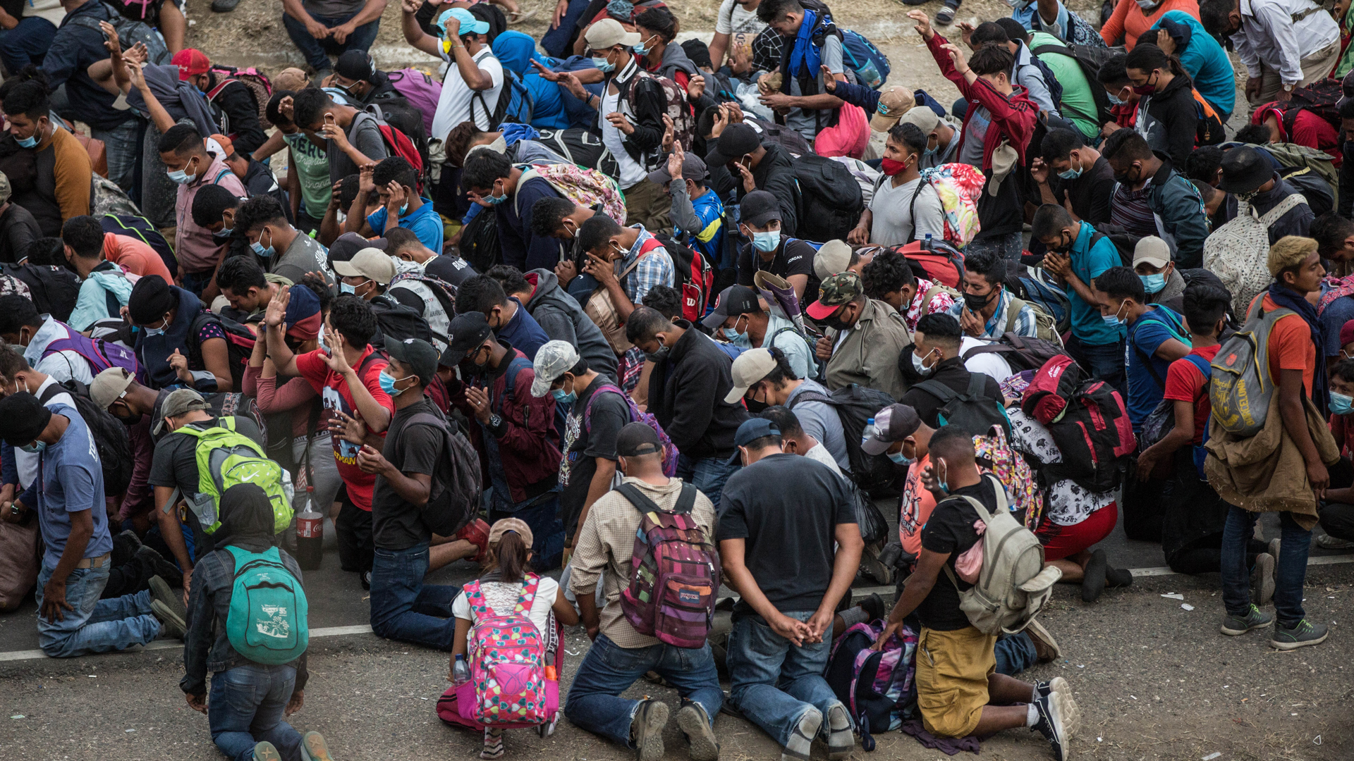 Miembros de caravana migrante hondureña dan positivo a COVID-19 - migrantes-hondurenos-rezan-frente-a-policias-de-guatemala-para-que-les-permitan-el-paso