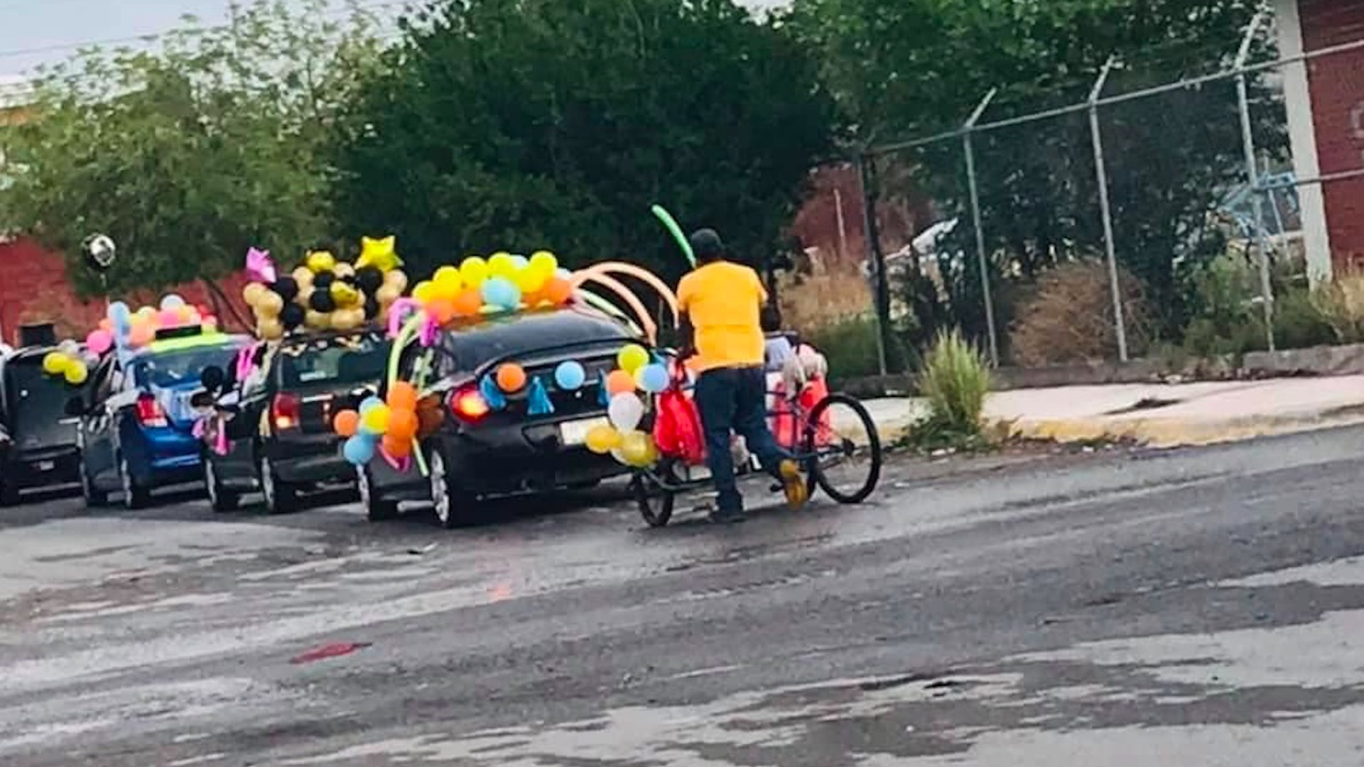 Hombre lleva a sus hijos a caravana de fin de cursos en triciclo - hombre-caravana-triciclo